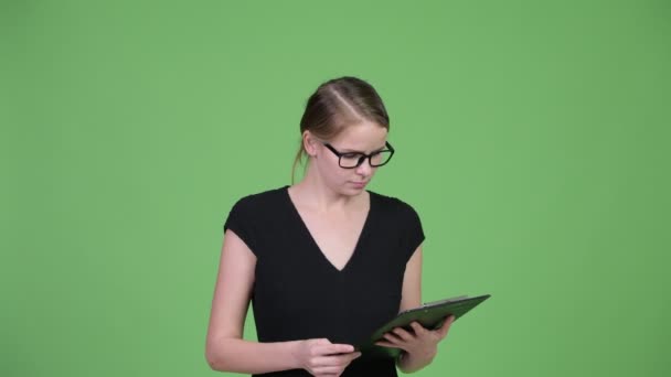 Junge schöne Geschäftsfrau liest auf Klemmbrett und sieht überrascht aus — Stockvideo