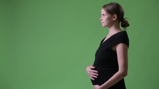 Vue du profil de jeune belle femme d'affaires enceinte sur fond vert — Video