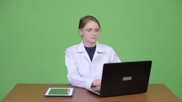 Ung vacker kvinna läkare med skyddsglasögon arbetar och hälsning någon — Stockvideo