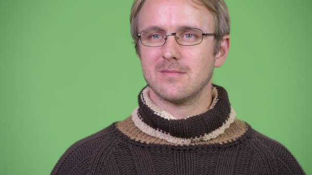 Ευτυχισμένος όμορφος άντρας σκέφτεται φορώντας ζιβάγκο πουλόβερ και γυαλιά — Αρχείο Βίντεο