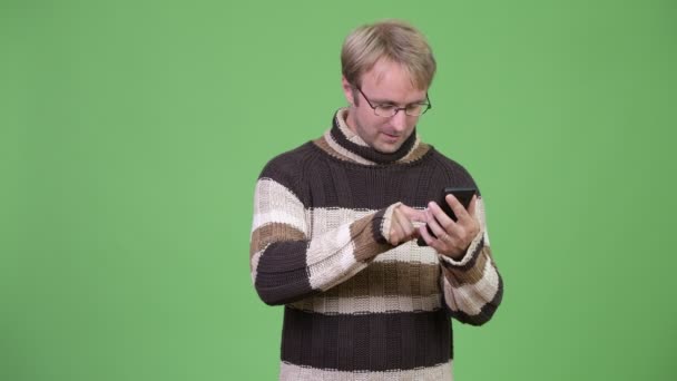 Estudio de tiro de hombre guapo feliz usando el teléfono y recibiendo buenas noticias — Vídeos de Stock