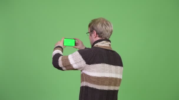 Вид сзади на блондинистого красавца, фотографирующего с телефона — стоковое видео