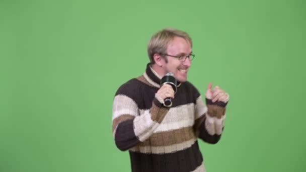 Estudio de tiro de hombre guapo feliz cantando con micrófono — Vídeos de Stock