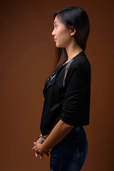 Junge schöne asiatische Frau vor braunem Hintergrund — Stockfoto