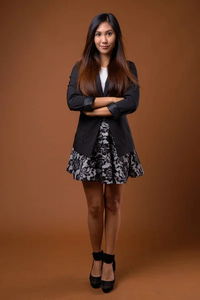 Jonge mooie Aziatische zakenvrouw tegen bruine achtergrond — Stockfoto