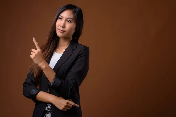 Joven hermosa mujer de negocios asiática contra fondo marrón —  Fotos de Stock
