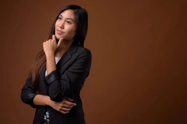 Jonge mooie Aziatische zakenvrouw tegen bruine achtergrond — Stockfoto