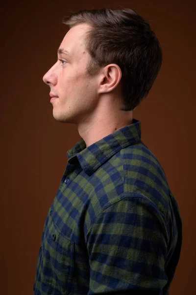 Fiatal jóképű férfi, barna háttér — Stock Fotó