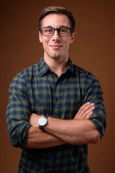 Young handsome man wearing eyeglasses against brown background — Stock Photo, Image