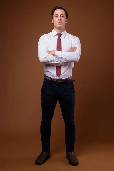 Young handsome businessman against brown background — Stock Photo, Image