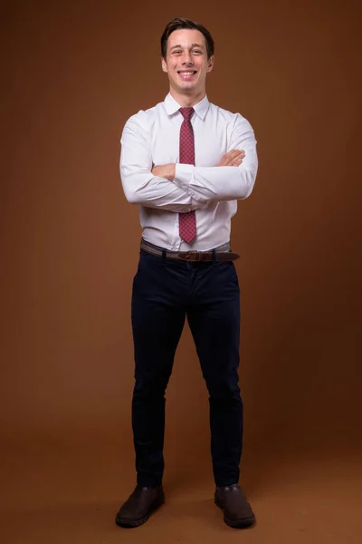 Young handsome businessman against brown background — Stock Photo, Image