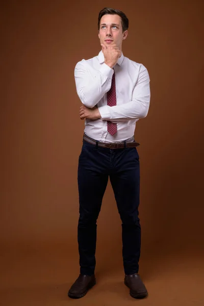 Young handsome businessman against brown background — Stock Photo, Image