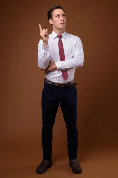 Young handsome businessman against brown background — Stock Photo, Image