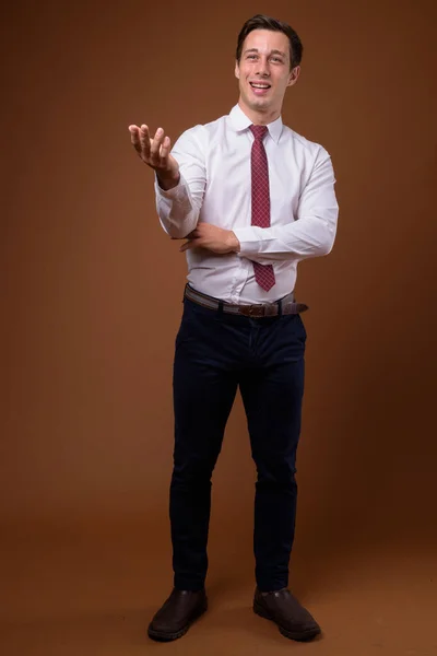 Young handsome businessman against brown background — Stock Photo, Image