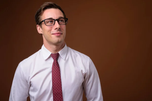 Junger gutaussehender Geschäftsmann mit Brille vor braunem Rücken — Stockfoto