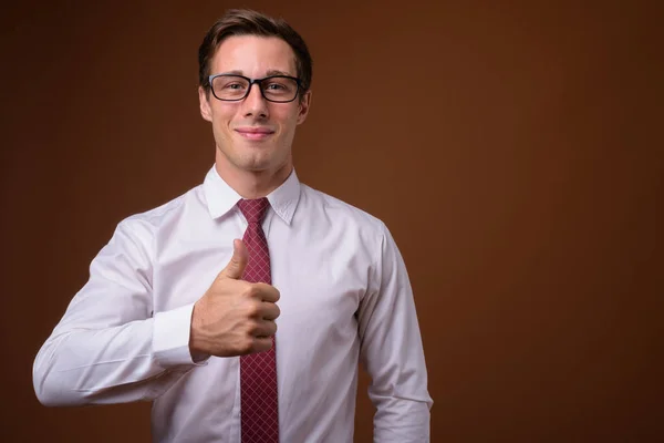 Jonge knappe zakenman dragen van bril tegen bruine rug — Stockfoto