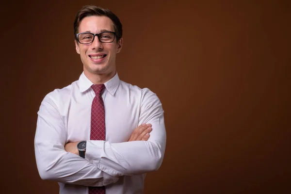 Young handsome businessman wearing eyeglasses against brown back — Stock Photo, Image