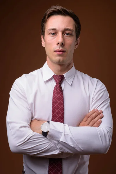 Junger gutaussehender Geschäftsmann mit braunem Hintergrund — Stockfoto