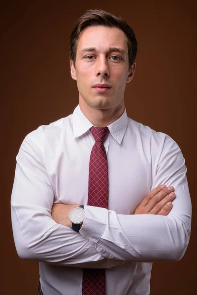 Young handsome businessman against brown background — Stock Photo, Image