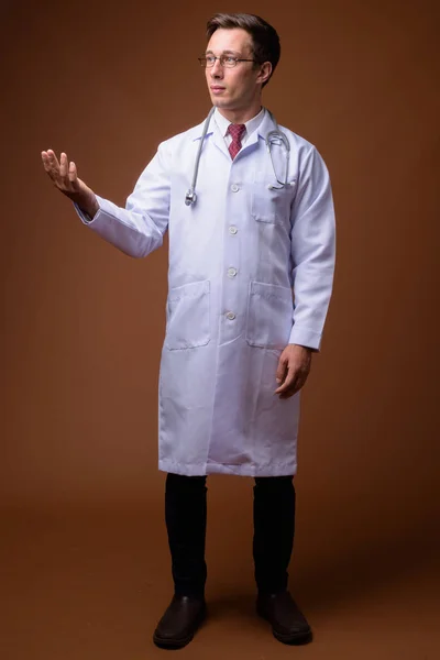 Giovane bell'uomo medico contro sfondo marrone — Foto Stock