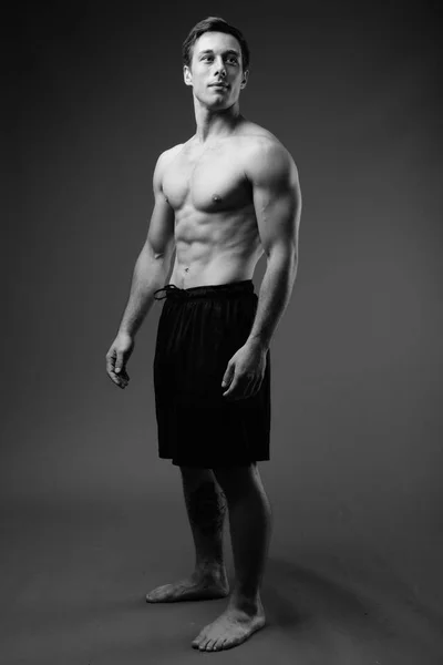 Studio colpo di giovane muscoloso bell'uomo a torso nudo in nero e — Foto Stock