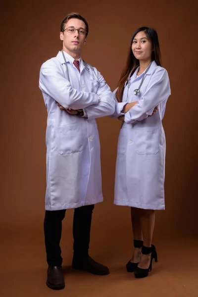 Два молодых врача вместе на коричневом фоне — стоковое фото