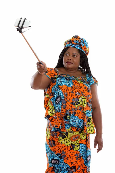 Fat black African woman standing while holding selfie stick and