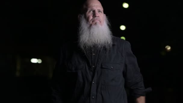 Портрет лысого человека с серой бородой ночью на открытом воздухе — стоковое видео