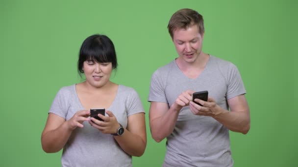 Jonge gelukkige multi-etnische paar gebruik van telefoon en samen denken — Stockvideo