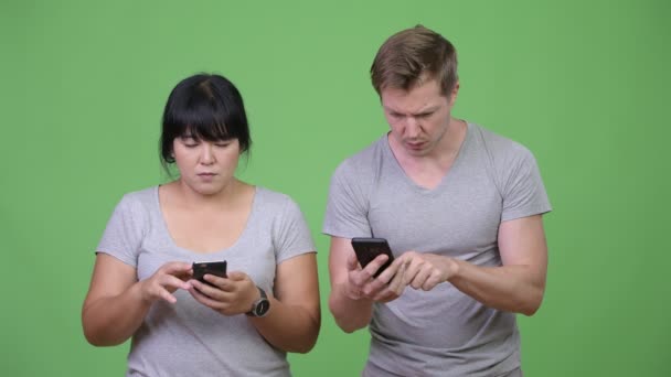 Young multi-ethnic couple using phone and getting bad news together — Stock Video
