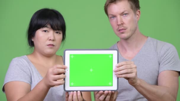 Genç mutlu çok etnik gruptan oluşan çift gösteren dijital tablet birlikte — Stok video