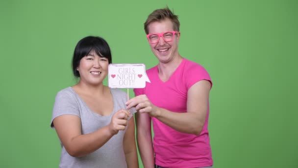 Overgewicht Aziatische vrouw en jonge homoseksuele man teken papier bij elkaar te houden — Stockvideo