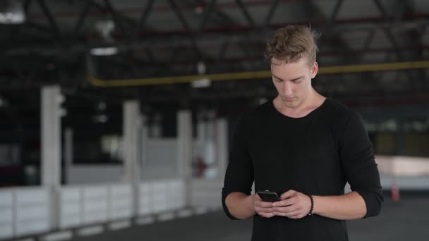 Young handsome man with curly hair using phone outdoors — Stock Video