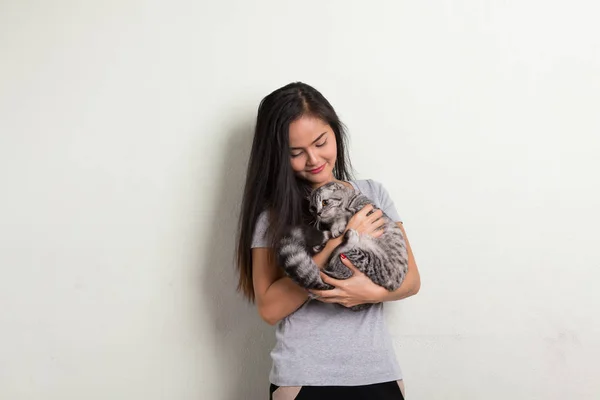 かわいい猫を保持しながら笑みを浮かべて若い幸せな美しいアジアの女性 — ストック写真