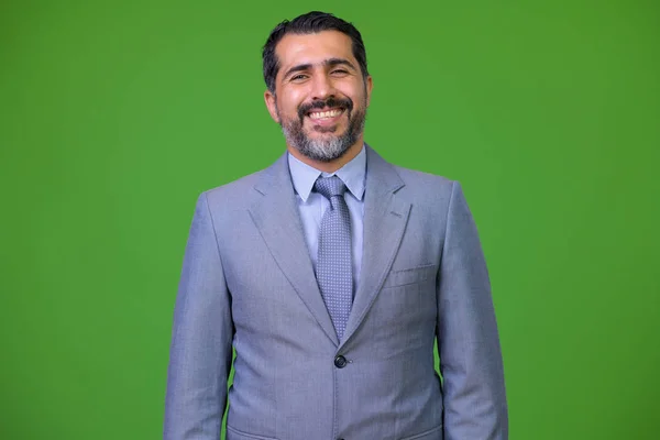 Handsome Persian bearded businessman against green background — Stock Photo, Image