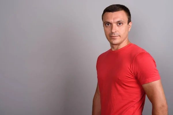 Muž na sobě červené tričko šedé pozadí — Stock fotografie