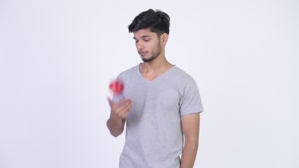 Genç yakışıklı aşağı Hintli adam yeme elma ve düşen sakallı — Stok video