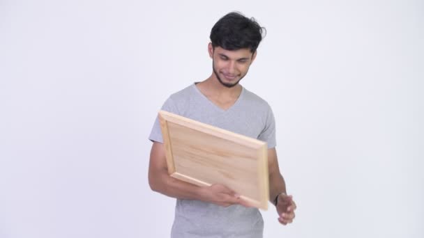 Ung glad skäggig indisk man visar blackboard och ger tummen — Stockvideo
