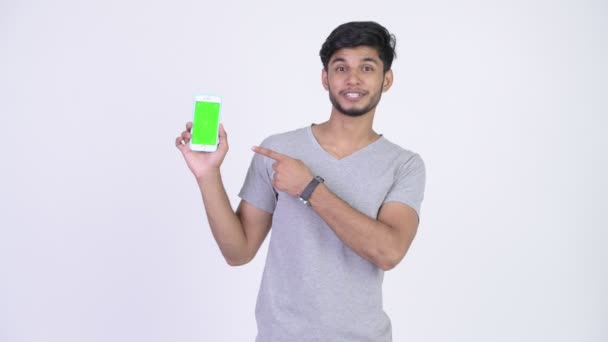 Молодой счастливый бородатый индеец показывает телефон и показывает большие пальцы вверх — стоковое видео