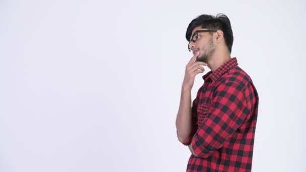 Profile view of young handsome bearded Indian hipster man thinking