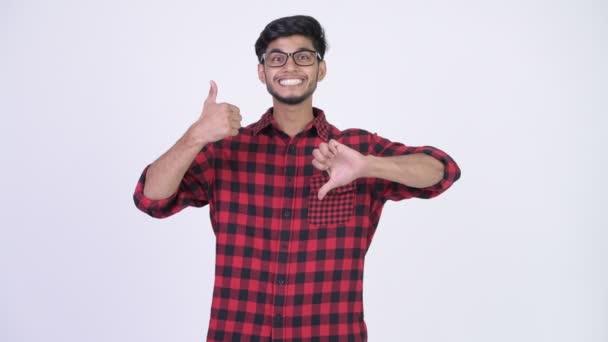 Young confused bearded Indian hipster man choosing between thumbs up and thumbs down — Stock Video