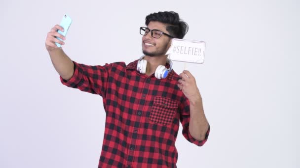 Молодой счастливый бородатый индийский хипстер делает селфи с бумажным знаком — стоковое видео