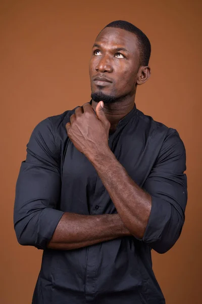 Porträtt av stilig afrikanska affärsman mot brun bakgrund — Stockfoto