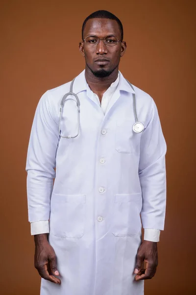 Bonito médico homem africano vestindo óculos contra o bac marrom — Fotografia de Stock