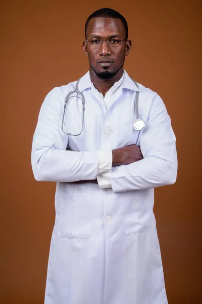 Bonito médico homem africano vestindo óculos contra o bac marrom — Fotografia de Stock