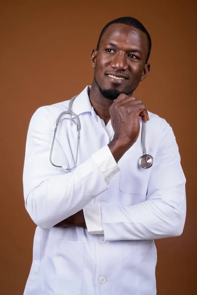 Bonito médico homem africano contra fundo marrom — Fotografia de Stock