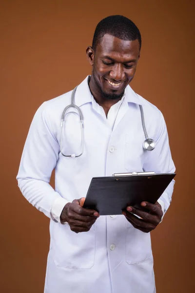 Handsome African man doctor against brown background — Stock Photo, Image