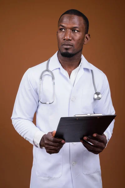 Bonito médico homem africano contra fundo marrom — Fotografia de Stock