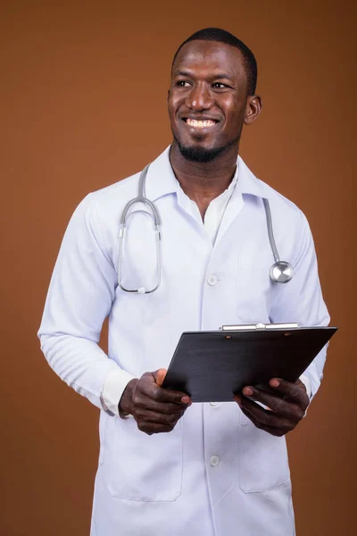 Bonito médico homem africano contra fundo marrom — Fotografia de Stock