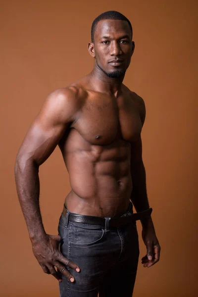 Yakışıklı kaslı Afrika adam kahverengi arka planı gömleksiz